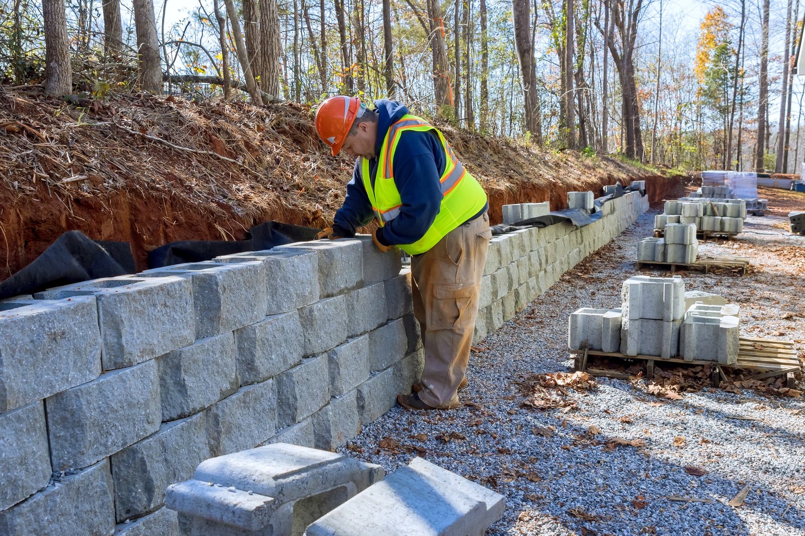Cement blocks are being used by construction worker to build a retaining wall during development of